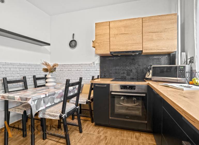 Konyha fa dekorációval, étkezőasztallal és háztartási gépekkel egy háromszobás lakásban.