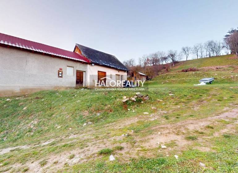 Családi ház Klenócon a domboldalon, mellette egy pad és zöld környezet.