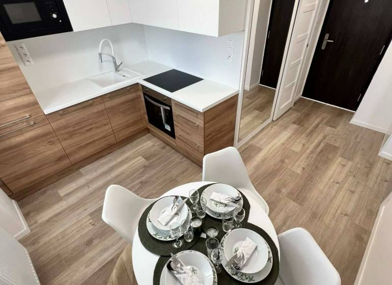 Konyha egy kétszobás lakásban fa dekor padlóval és étkezőasztallal.