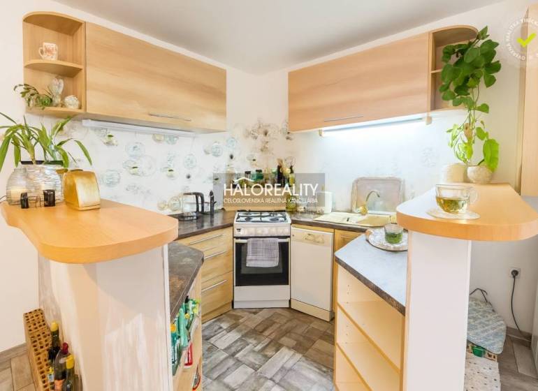 Konyha egy családi házban sarok konyhabútorral és fa dekorációval, dekoratív növényekkel a polcokon.