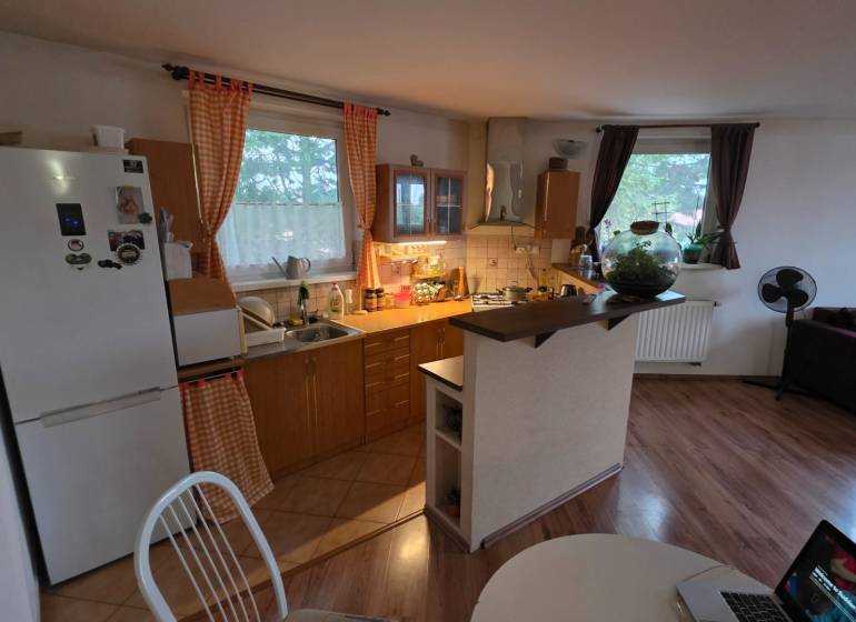 Konyha egy háromszobás lakásban fa dekor padlóval és étkezőasztallal.