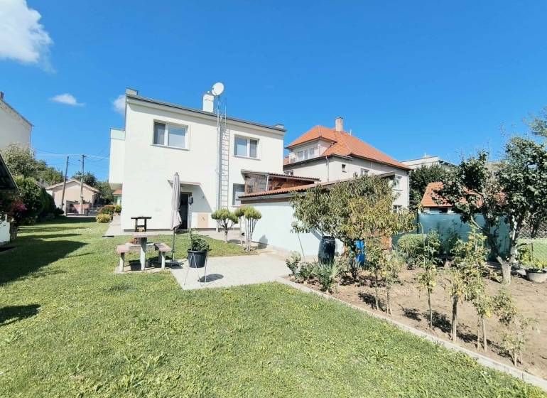 Családi ház Partizánskén, zöld gyep és kert veszi körül, kék ég alatt.