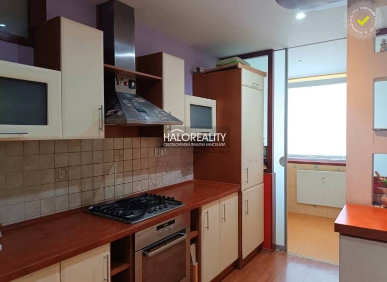 Garzonlakás konyhája gáztűzhellyel és üvegszekrényekkel.