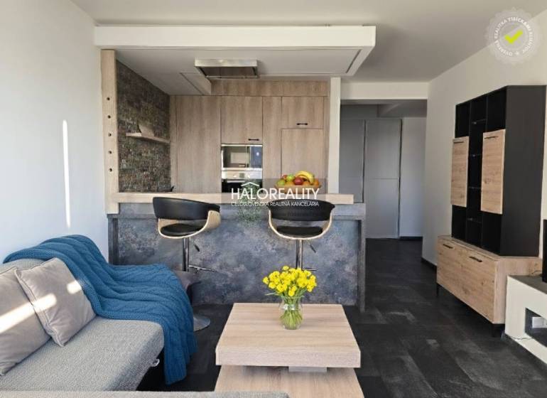 Nappali kétszobás lakásban nyitott konyhával és fa dekoros padlóval.