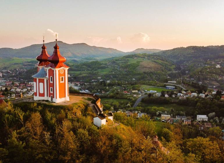 Kálvária a dombon Banská Štiavnica panorámájával, mezőgazdasági és erdészeti területekkel körülvéve.