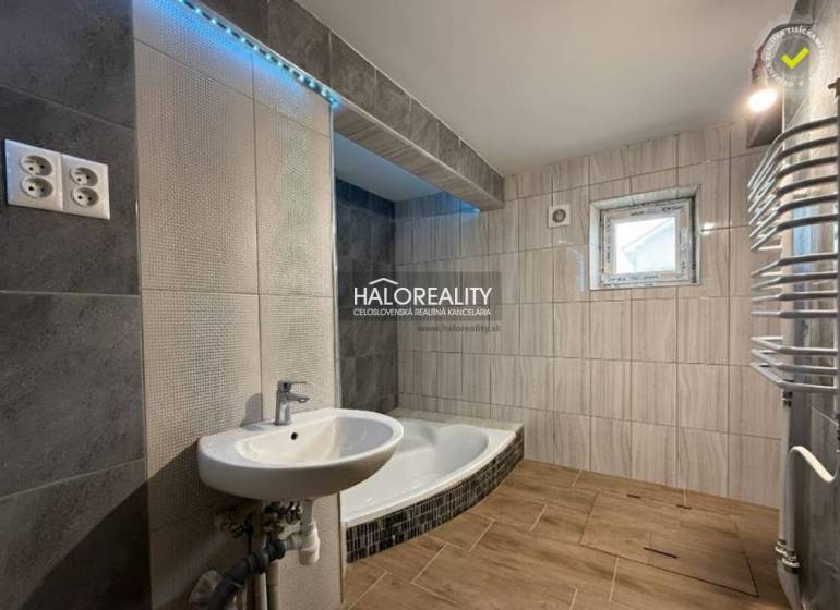 Családi ház fürdőszobája káddal, mosdóval és fa dekoros padlóval.