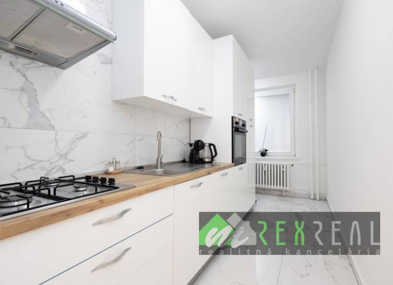 Konyha fehér szekrényekkel, márvány padlóval és beépített készülékekkel egy háromszobás lakásban.