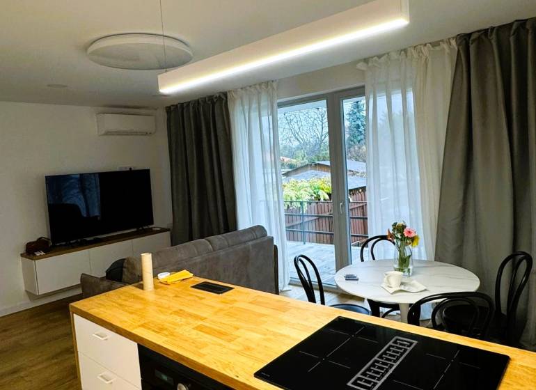 Konyhasziget főzőlappal, étkezőasztal és kanapé egy családi házban.