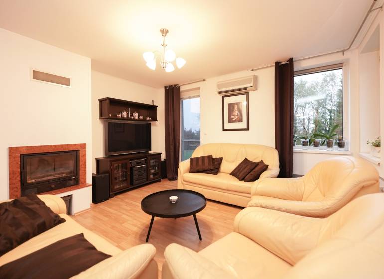 Nappali egy családi házban kandallóval, bőr kanapékkal és fa dekorációjú padlóval.