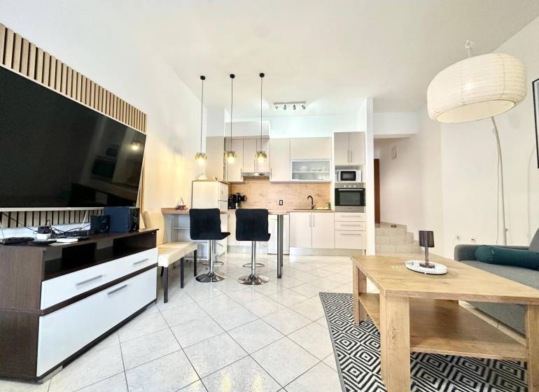 Rekreációs apartman tágas nappalival, konyhával és televízióval.