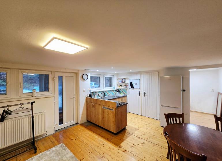 Konyha egy egyszobás lakásban, fa dekoros padlóval és asztallal.