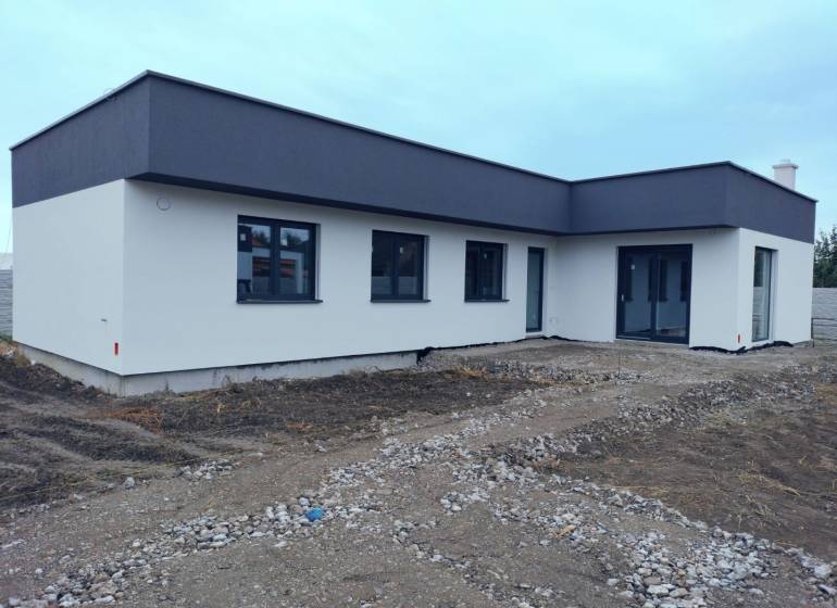 Lapos tetős, világos homlokzatú családi ház Zsigárdon.