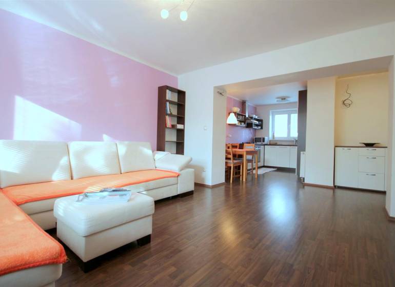 Nappali egy kétszobás lakásban sarokkanapéval és fa dekorációjú padlóval.