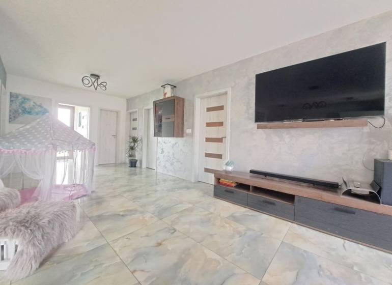 Nappali családi házban, falra szerelt televízióval, sátorral és kerámia padlóval.