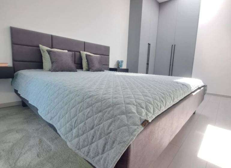 Hálószoba egy kétszobás lakásban felső ablakból érkező fénnyel és minimalista berendezéssel.