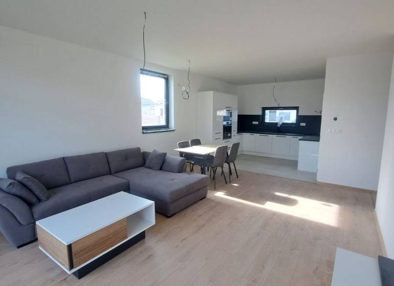 Nappali családi házban konyhával, kanapéval és fa dekorú padlóval.