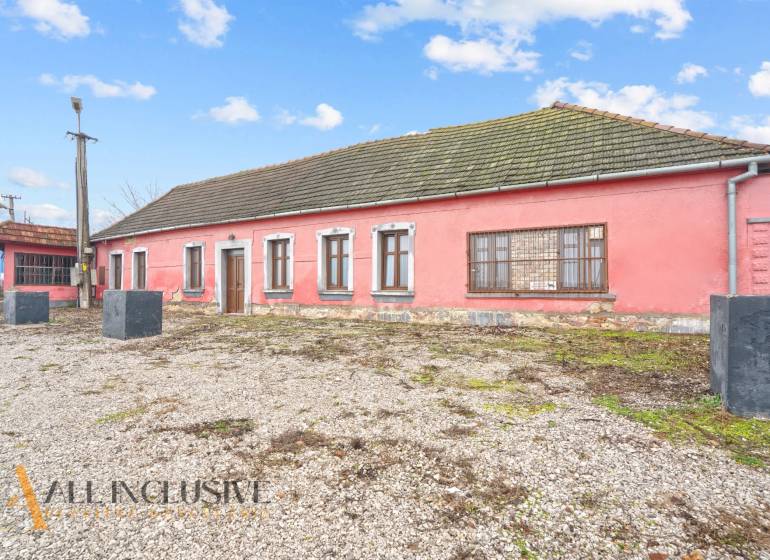 Családi ház Sempteben kőalappal, rózsaszín homlokzattal és fa ablakokkal.