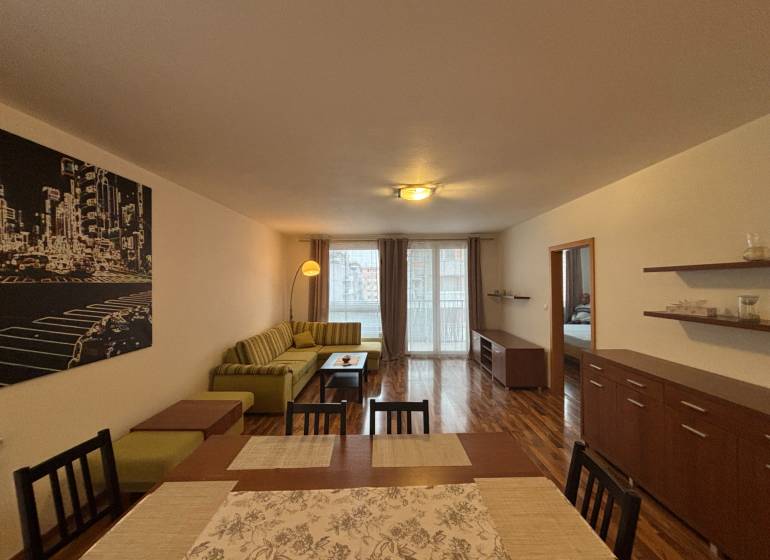 Nappali fa mintázatú padlóval, kanapéval és étkezőasztallal egy kétszobás lakásban.