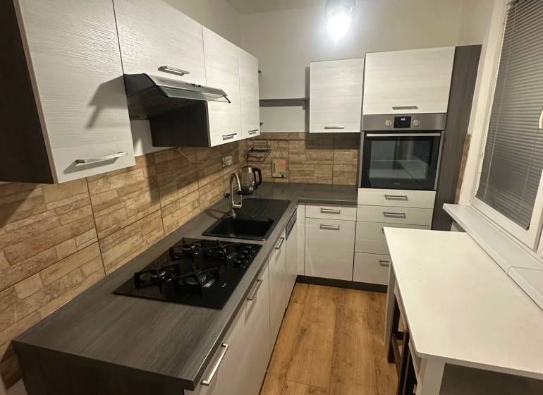 Konyha egy kétszobás lakásban, fa dekoros padlóval és téglafalakkal.