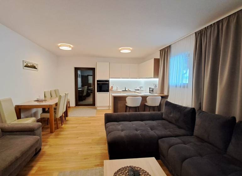 Nappali kétszobás lakásban konyhával, étkezőasztallal és fa dekorációjú padlóval.