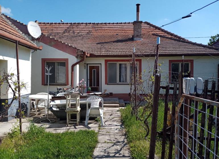 Családi ház Érsekújváron terasszal, műanyag székekkel és műholdas antennával.