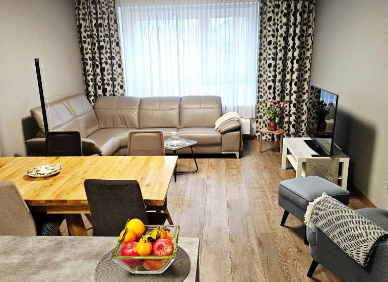 Nappali egy háromszobás lakásban bőrkanapéval és fa dekorációjú padlóval.