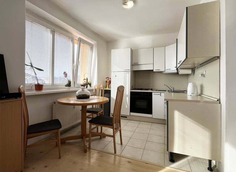 Konyha egy egyszobás lakásban, kerek asztallal és fa dekorációjú padlóval.