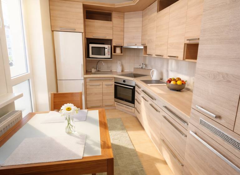 Konyha egy kétszobás lakásban fa dekorációval, étkezőasztallal és modern készülékekkel.