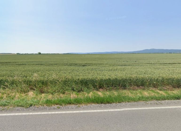 Mezőgazdasági és erdőterületek Budmericen kiterjedt mezőkkel és távoli dombokkal.
