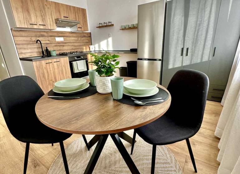 Konyhasarok az egyszobás lakásban fa dekorációval és kerek asztallal.