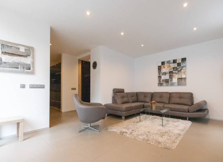 Nappali egy kétszobás lakásban kanapéval, fotellel, szőnyeggel és képekkel a falon.