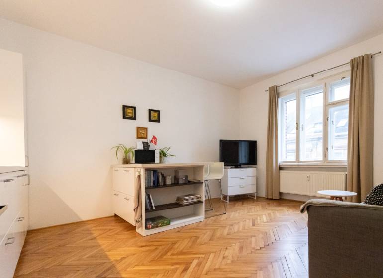 Nappali egy kétszobás lakásban világos bútorokkal és fa dekorációjú padlóval.