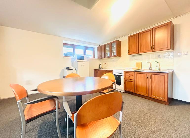 Konyha egy családi házban étkezőasztallal, székekkel és fa dekorációjú konyhabútorral.