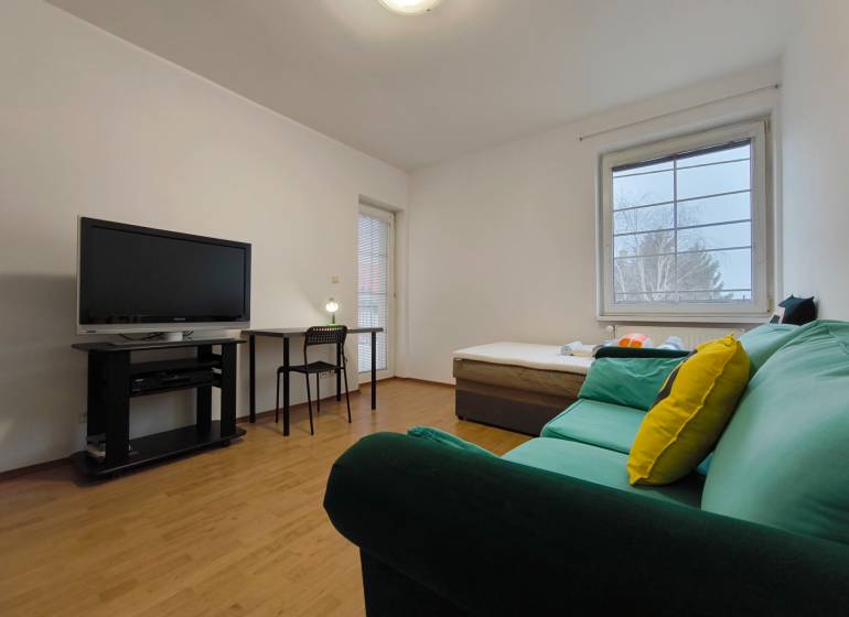 Nappali egy családi házban kanapéval, televízióval, asztallal és fa dekorációjú padlóval.