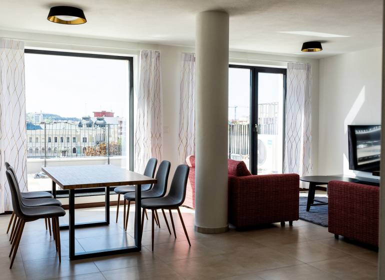 A háromszobás lakás nappalija étkezőasztallal és kilátással a városra.