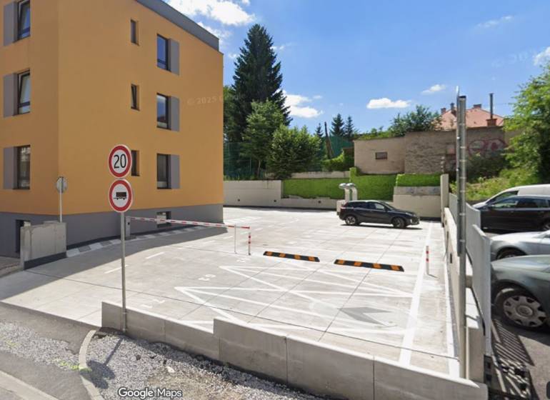 Parkoló és lakóépület a Rudlovská úton Besztercebányán, zölddel körülvéve.