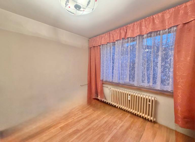 Szoba egy háromszobás lakásban fa dekor padlóval és függönyökkel.