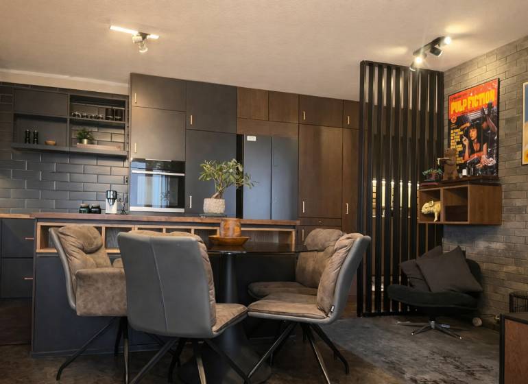 Konyha egy kétszobás lakásban sötét szekrényekkel és dekoratív poszterekkel a falon.