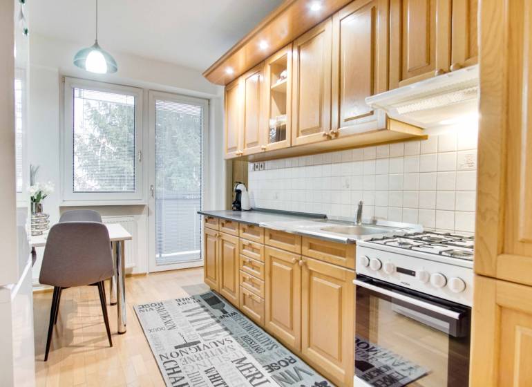 Konyha egy 4 szobás lakásban fa mintázatú padlóval és étkezőasztallal.