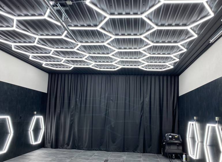 Sötét dekorral rendelkező üzlethelyiség hatszögletű LED világítással a mennyezeten és a falakon.