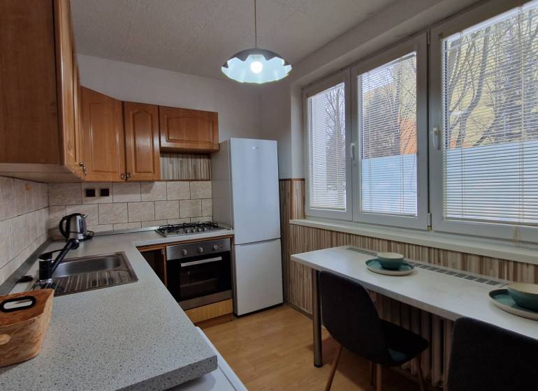 Konyha egy 2 szobás lakásban, fa dekoros padlóval és háztartási gépekkel.