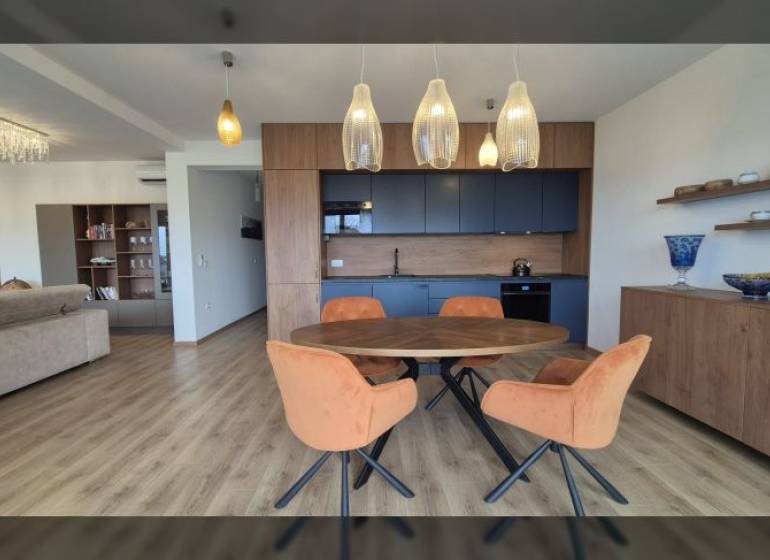 Nyaraló apartman belső tere fa mintázatú padlóval és étkezőasztallal.