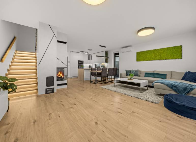 Nappali egy négy szobás lakásban, fa dekoros padlóval, kandallóval és modern lépcsővel.