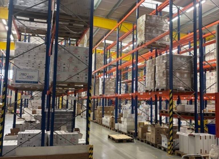 Raktárak és csarnokok polcai tele raklapokon tárolt árukkal.