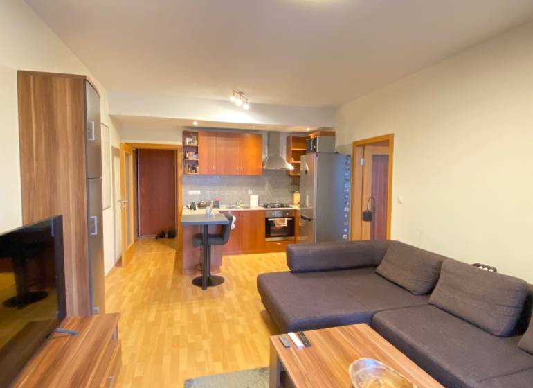 Nappali egy kétszobás lakásban, fa mintás padlóval és kanapéval.