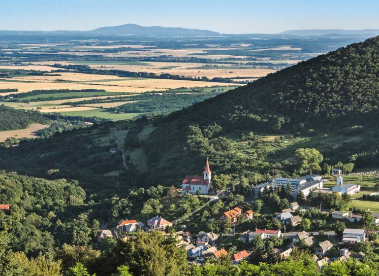 Panorámás kilátás egy falura a völgyben, erdőkkel és mezőkkel körülvéve. Lakhatásra alkalmas telkek.