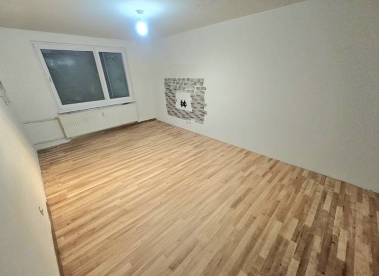 Nappali szoba fa dekor padlóval és ablakkal egy háromszobás lakásban.