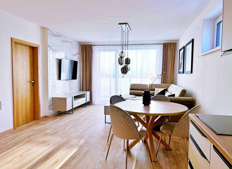 Nappali egy háromszobás lakásban világos bútorokkal és fa dekorációjú padlóval.