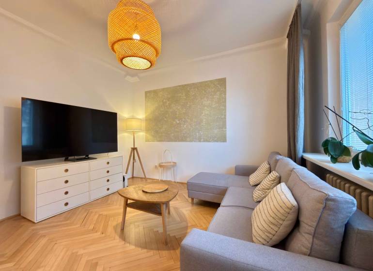 Nappali egy kétszobás lakásban fa mintázatú padlóval, kanapéval és TV-vel.