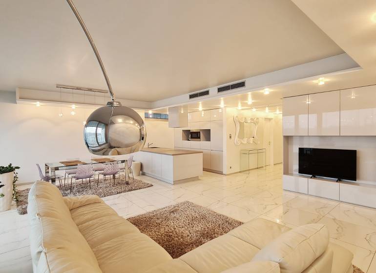 3 szobás lakás belső tere nyitott konyhával és fehér ülőgarnitúrával.